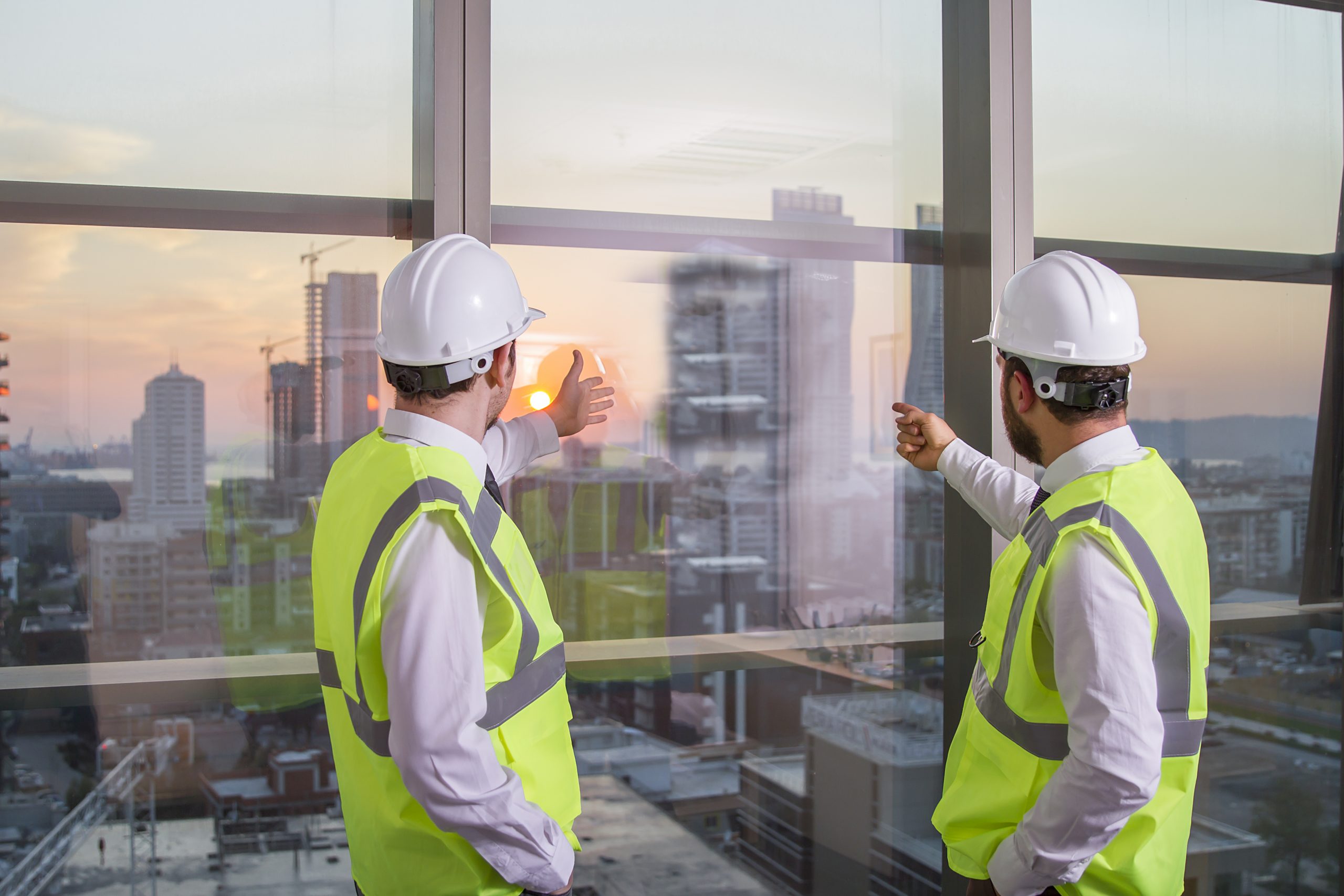 two workers inspecting glass in high rise building